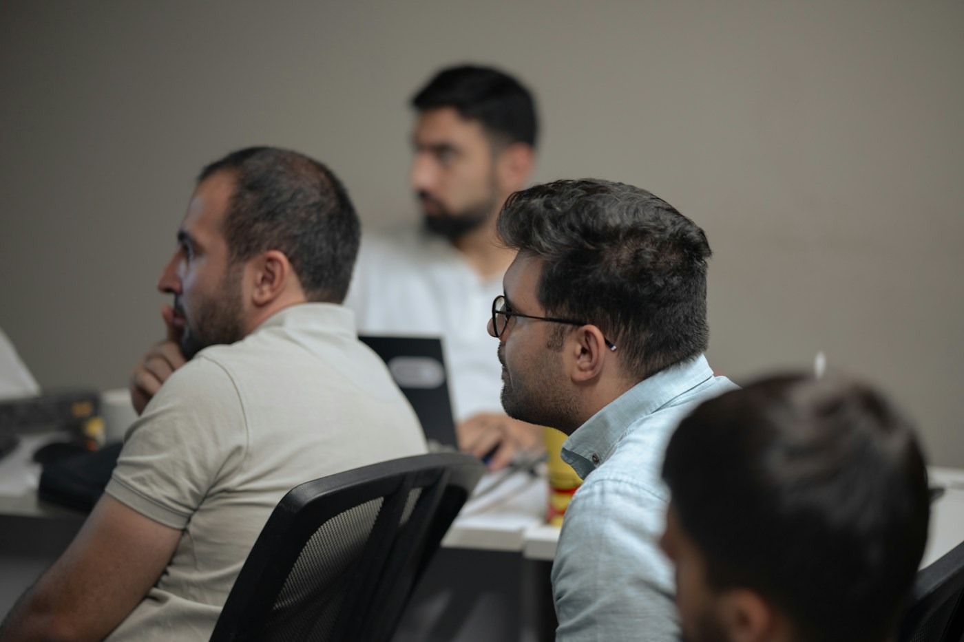 Colleagues around a meeting table with laptops, listening to a discussion.