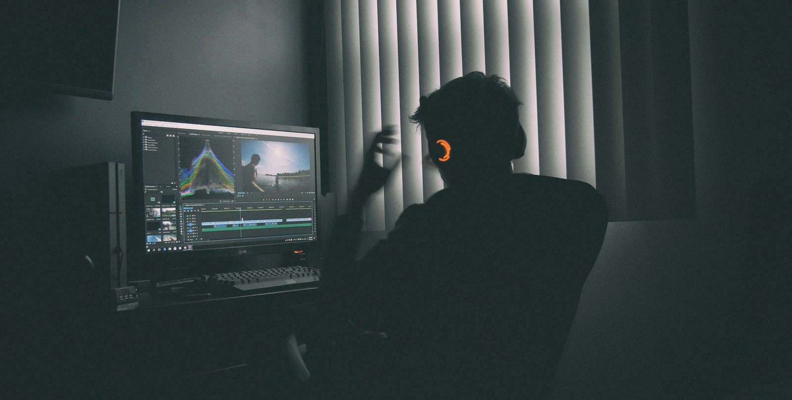 An editor in headphones working at a screen in a dark edit suite