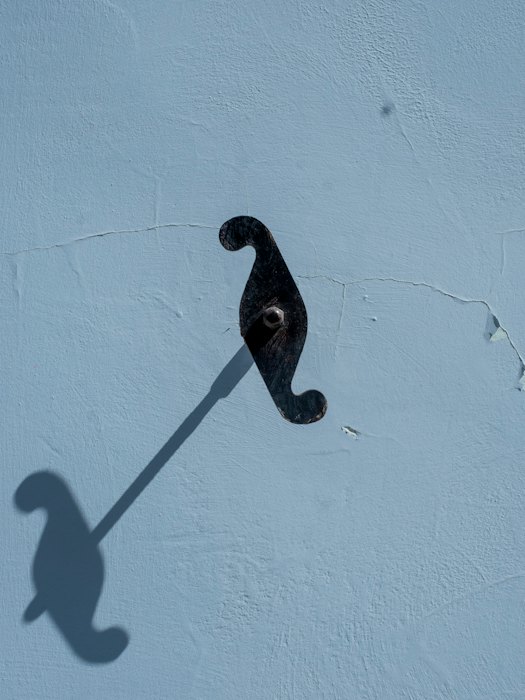 A sculptural object casting a long shadow on a wall