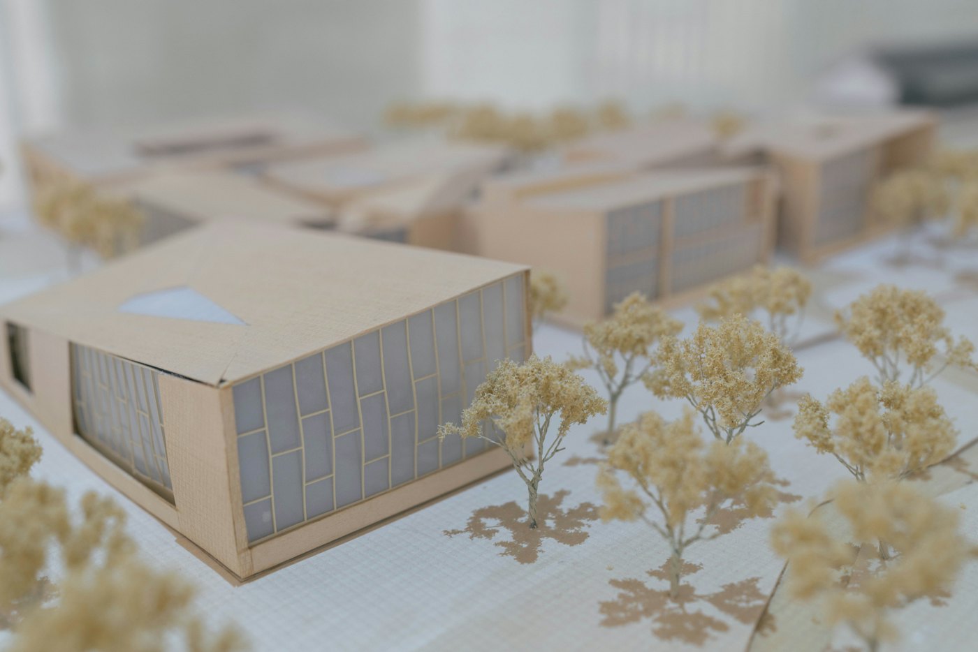 A card and paper site model of low buildings among model trees on a gridded base