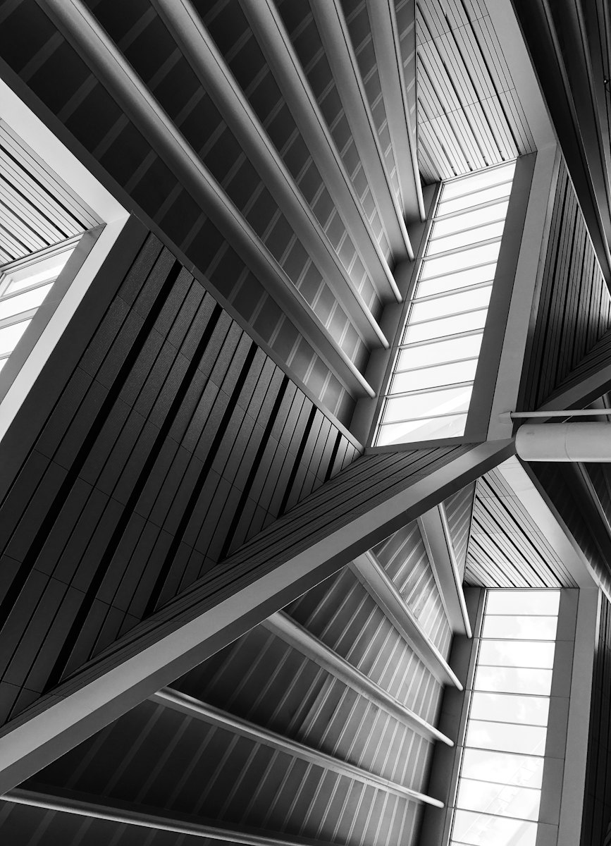 Looking up into a steel roof structure where repeating beams meet in clear lines