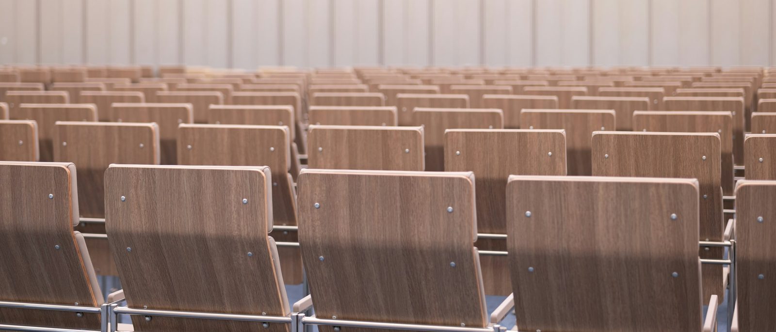 Rows of empty wooden seats facing the front of a pale, quiet hall