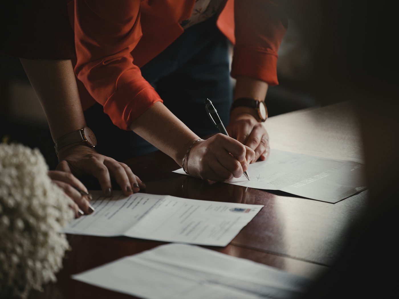 Hands signing printed pages on a meeting table
