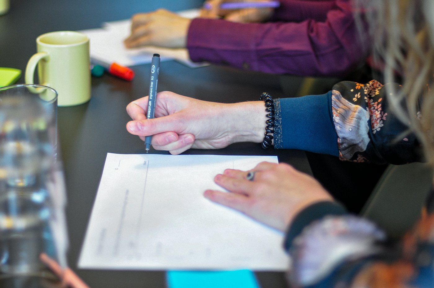 Hands resting on printed pages around a meeting table during a working session