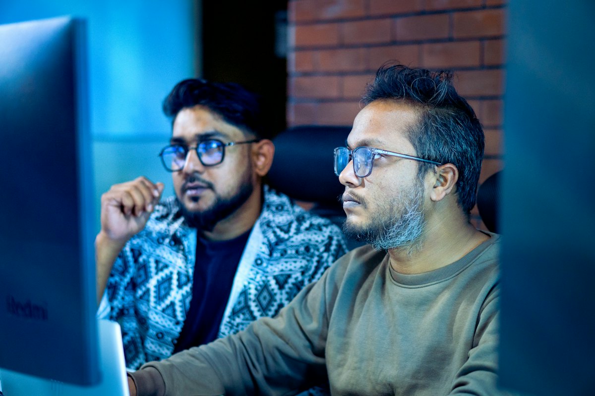 Two colleagues reviewing work together on a desktop monitor