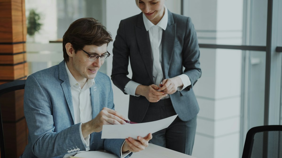 Two colleagues reviewing printed documents together at a table