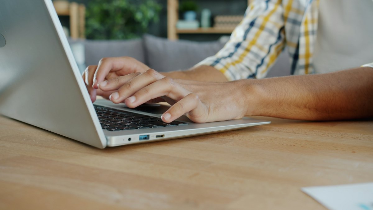 Hands working on a laptop at a desk