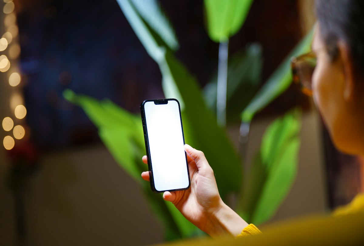 A hand holding a phone with a blank screen in soft light