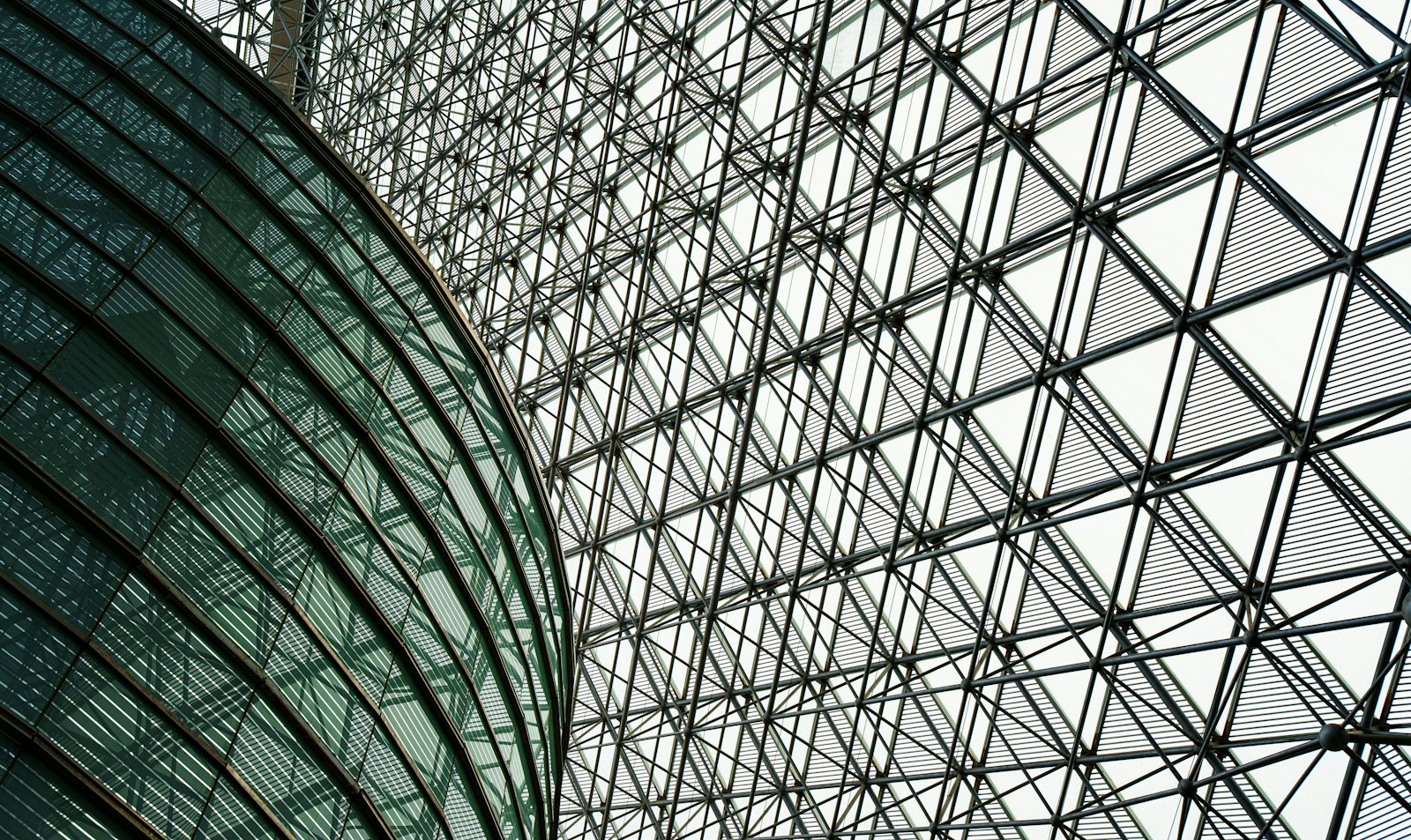 Looking up through the steel and glass lattice of a large public roof