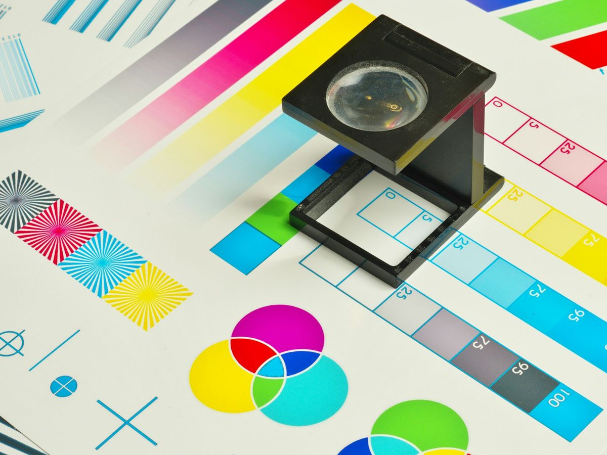 A linen tester magnifier resting on a printed colour calibration chart