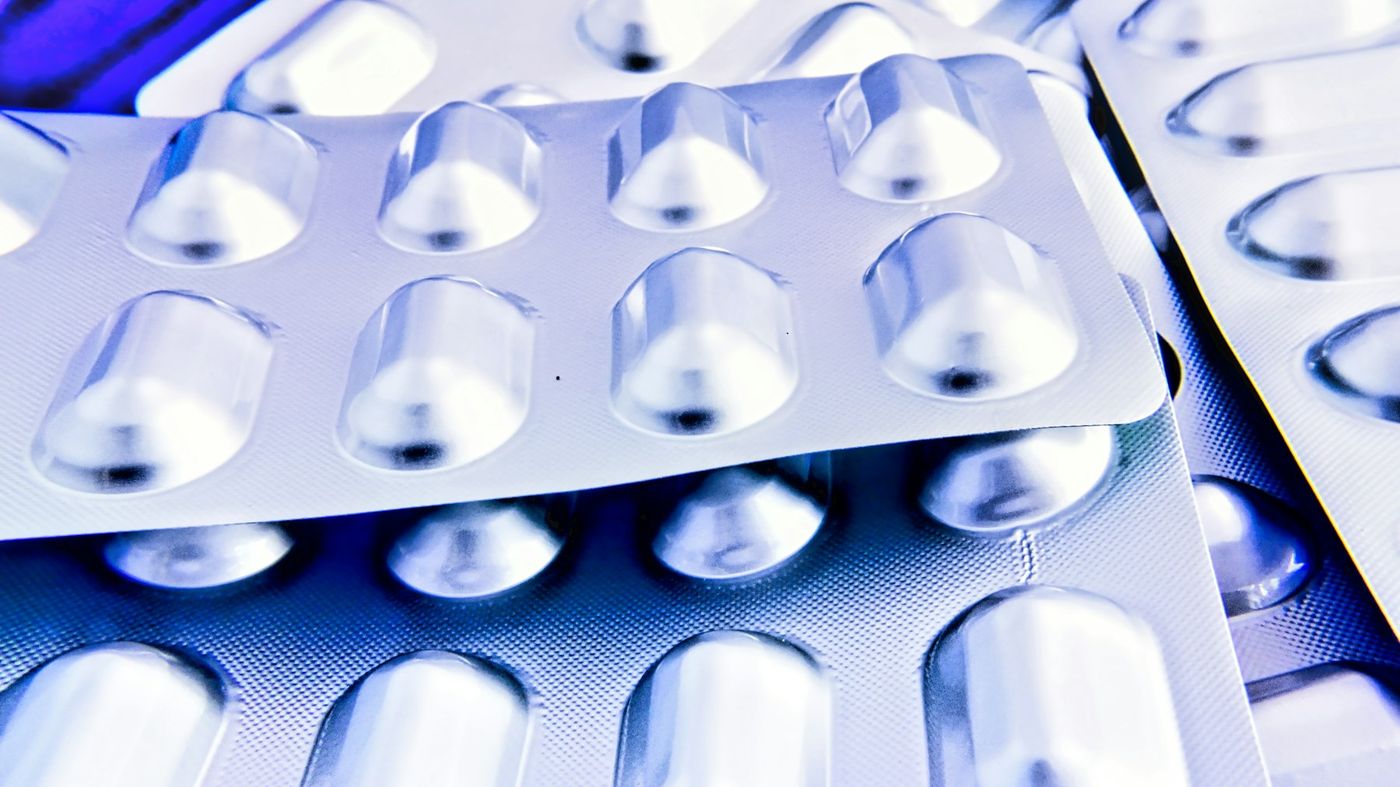 Stacked blister packs of capsules lit in cool blue light