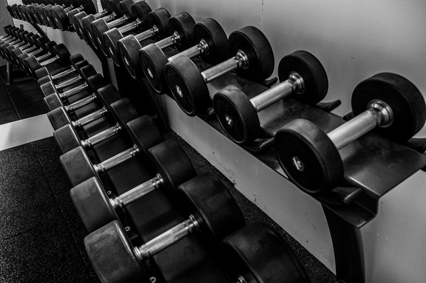 Rows of dumbbells on a rack in a gym, in black and white