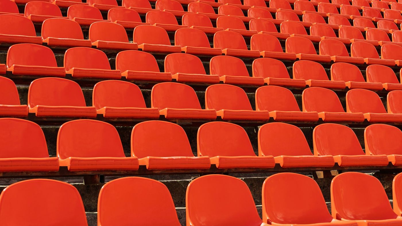 Rows of empty red plastic seats in a stadium stand