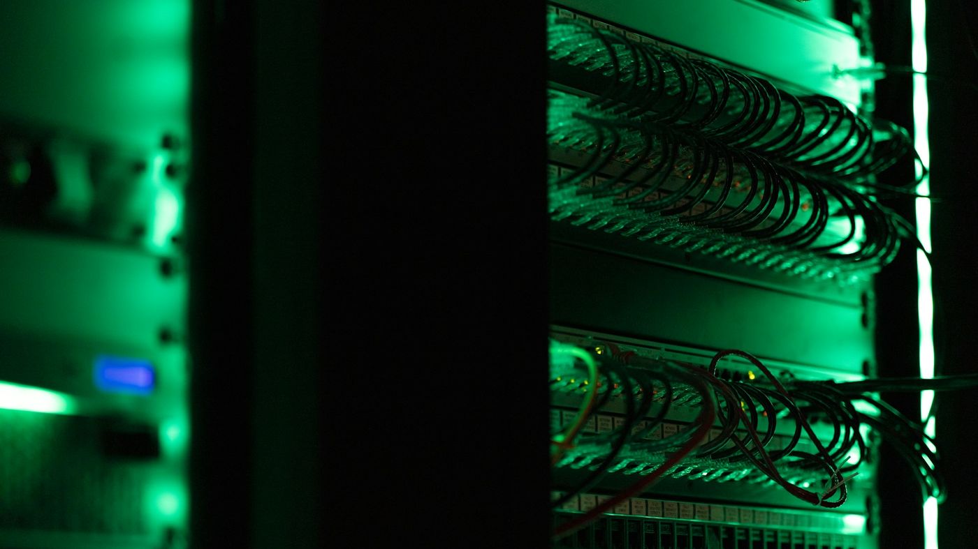 Network cables and equipment in a server rack, lit green in the dark