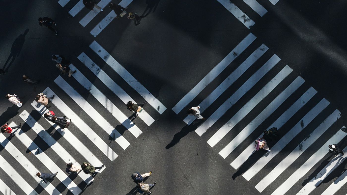 An aerial view of people crossing a large intersection on striped crossings