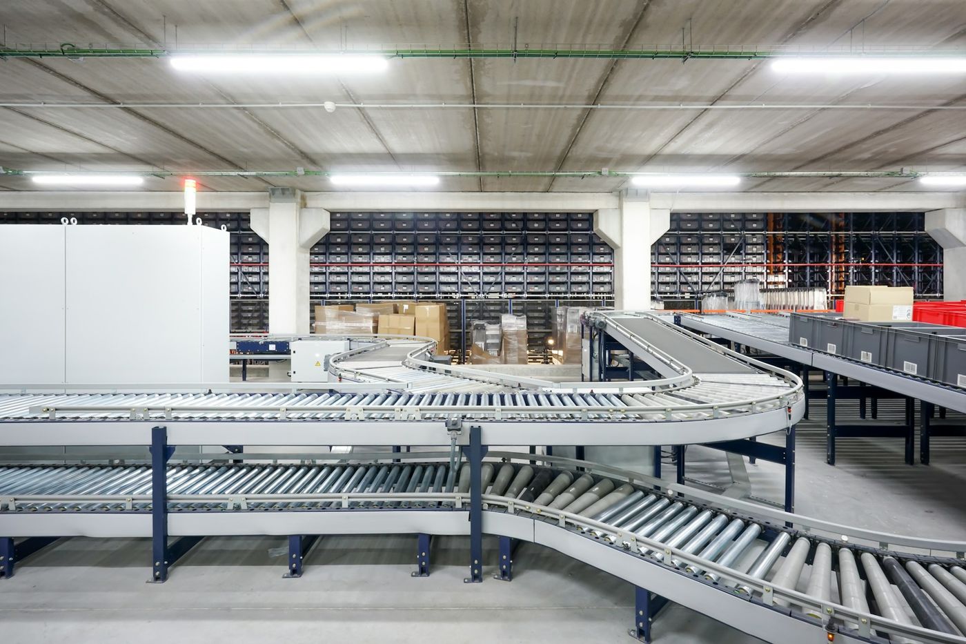 Curved roller conveyors run through an empty, brightly lit warehouse