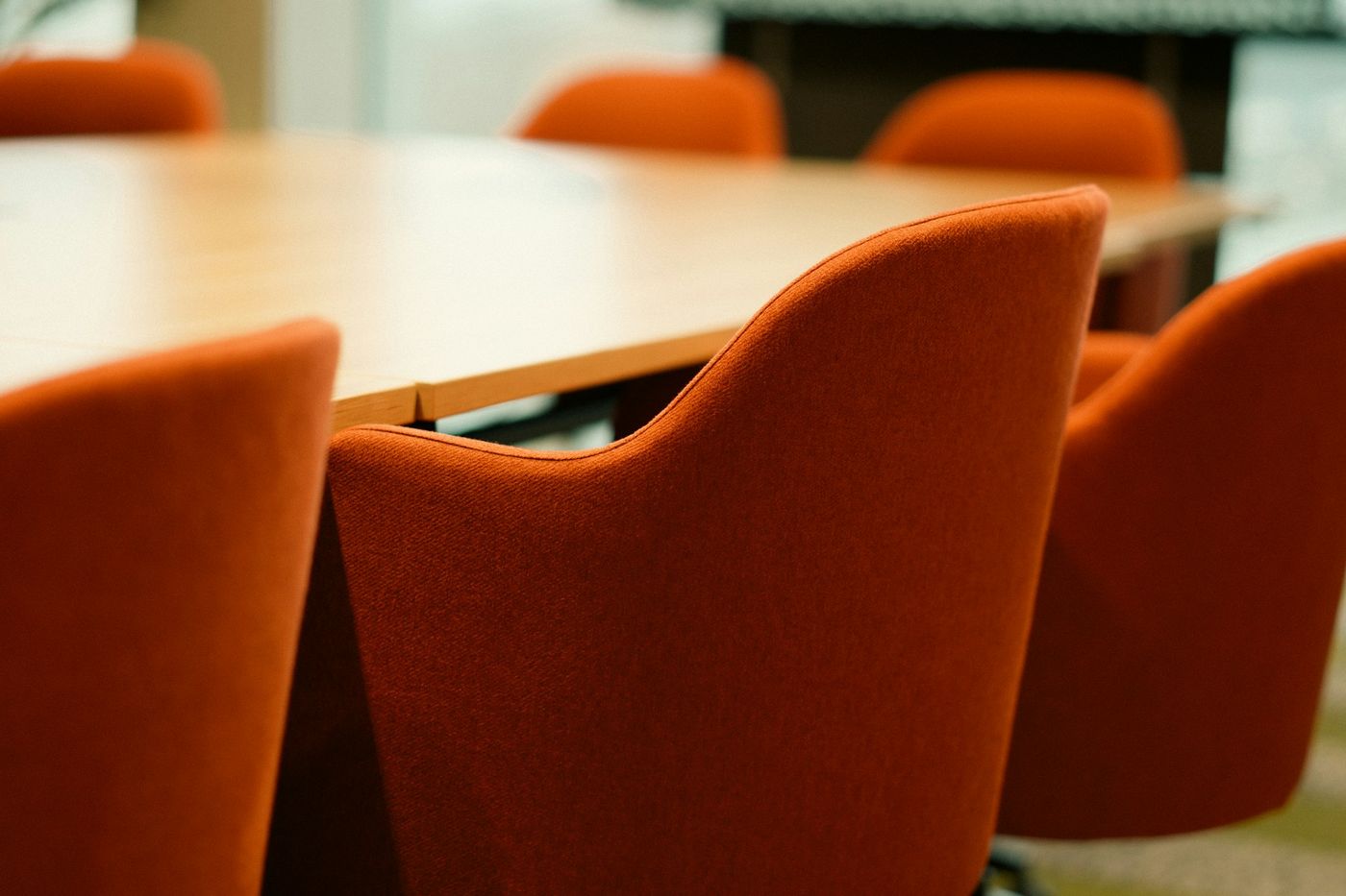 Orange upholstered chairs around a wooden meeting table
