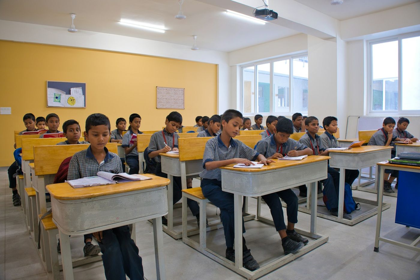 Schoolchildren in uniform study at desks in a bright classroom