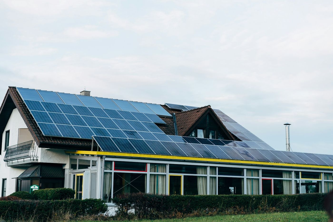 A house with its roof covered in solar panels under a pale sky