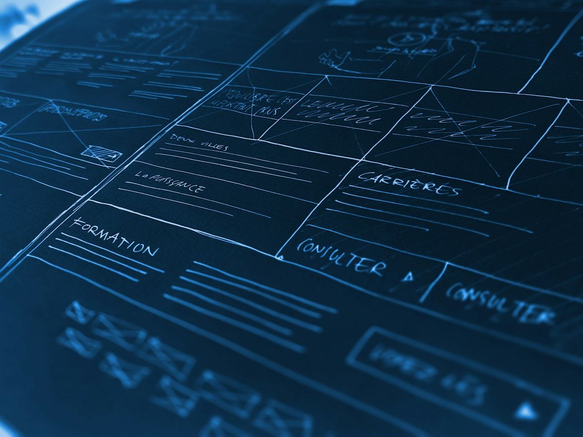 Hand-drawn wireframes of page layouts in white lines on a deep blue ground