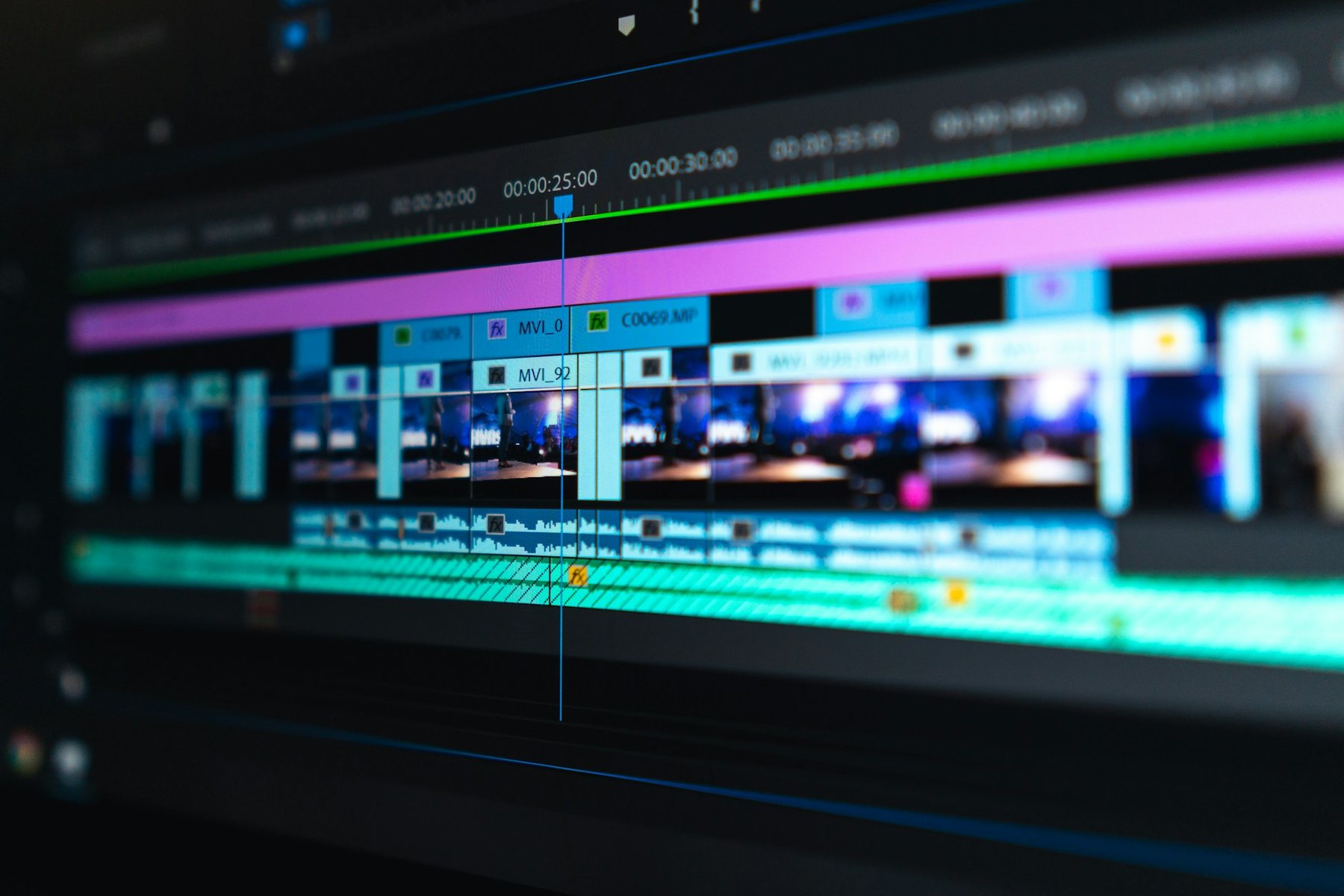 An edit timeline on a monitor, video clips and audio tracks stacked under the playhead