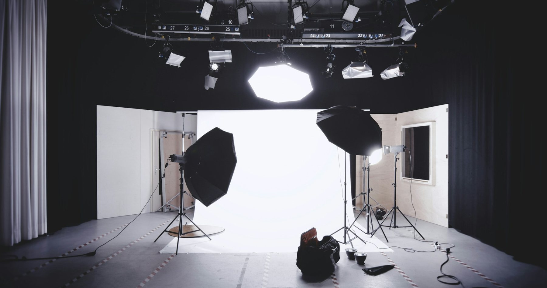 A photo studio with octagonal soft boxes, strobes and an overhead lighting grid around a white paper backdrop