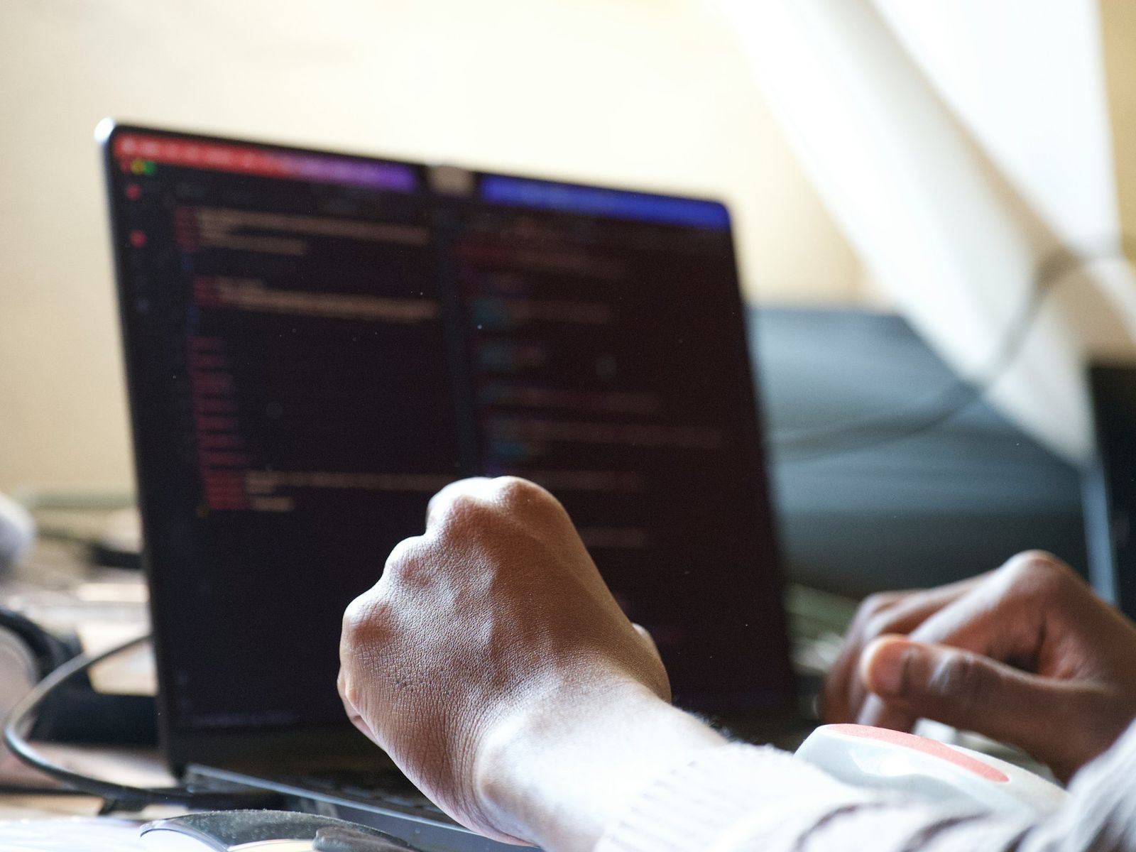 Hands typing code on a laptop, the editor dark on the screen.