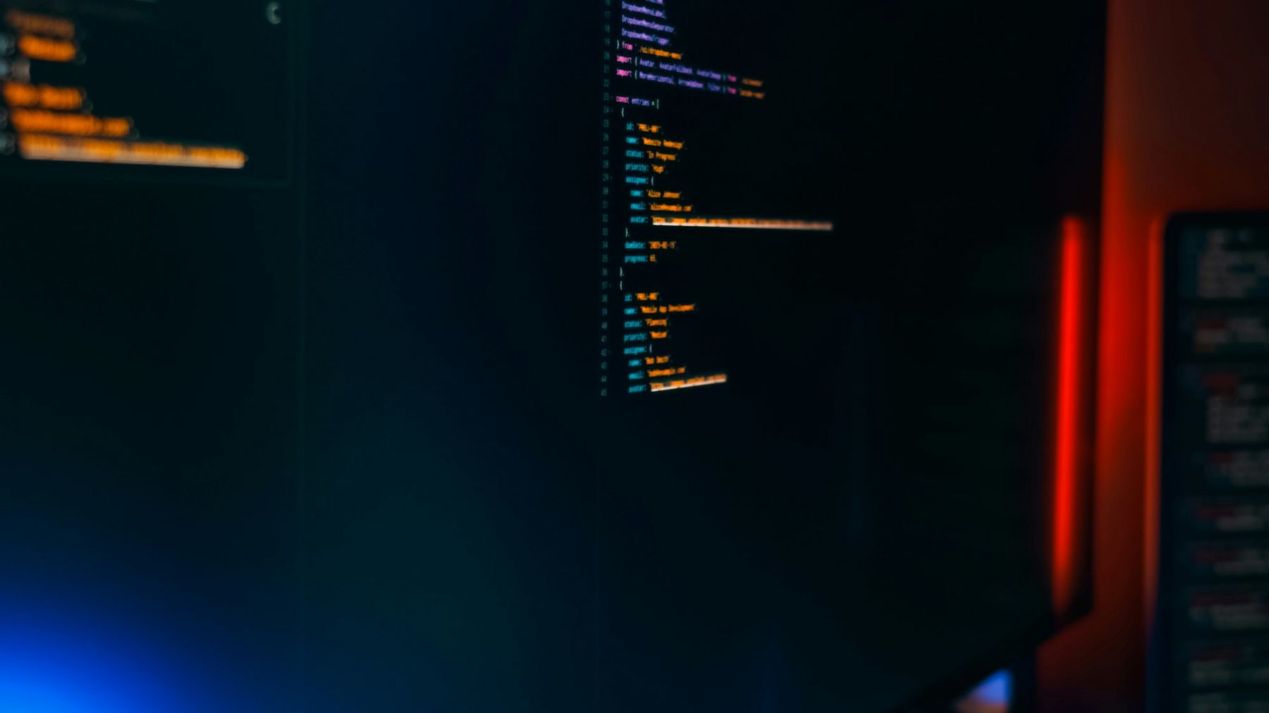 Source code on a dark monitor in a dim room lit by a red and blue glow