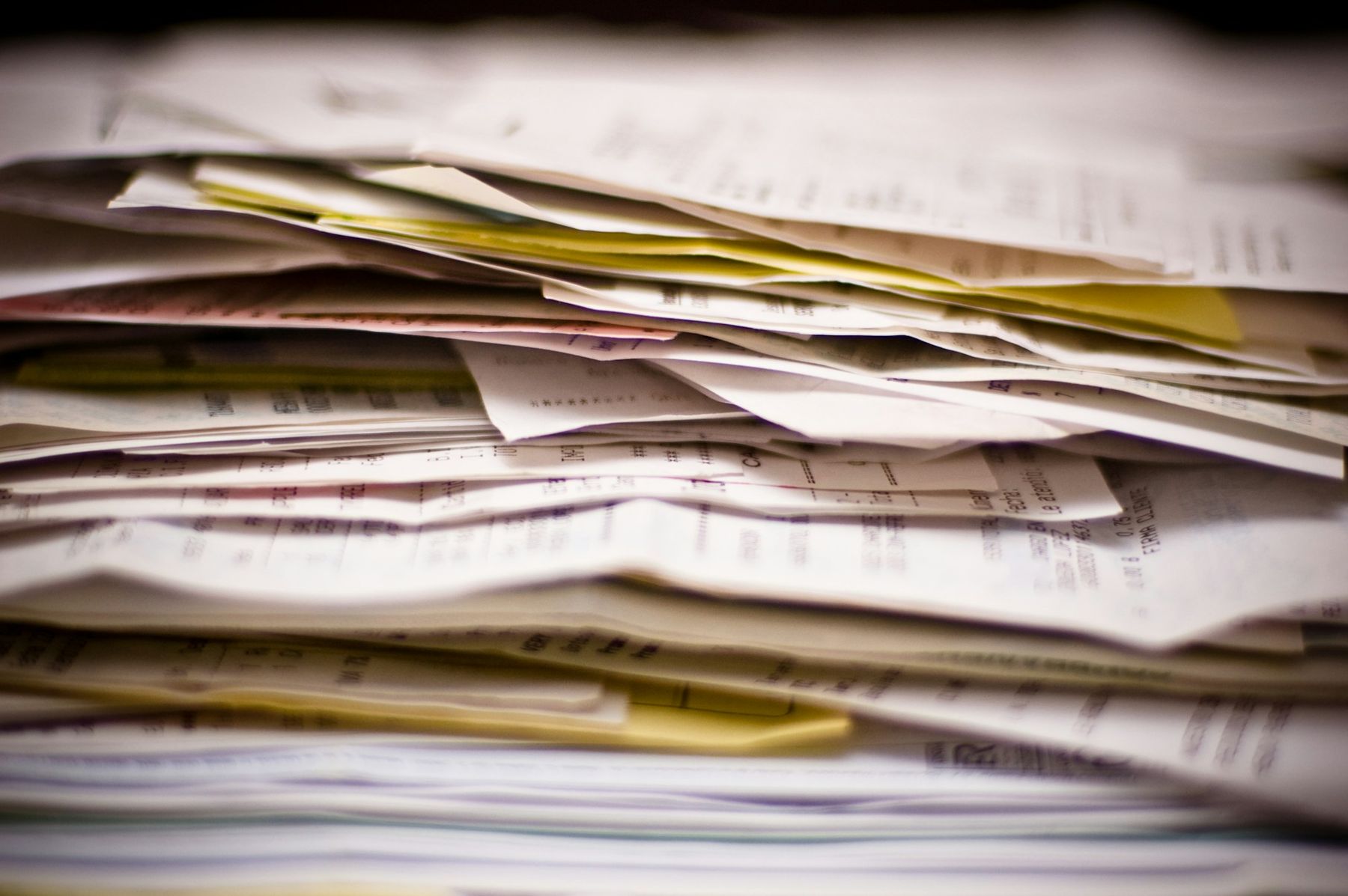 A thick, uneven stack of printed invoices, receipts and forms