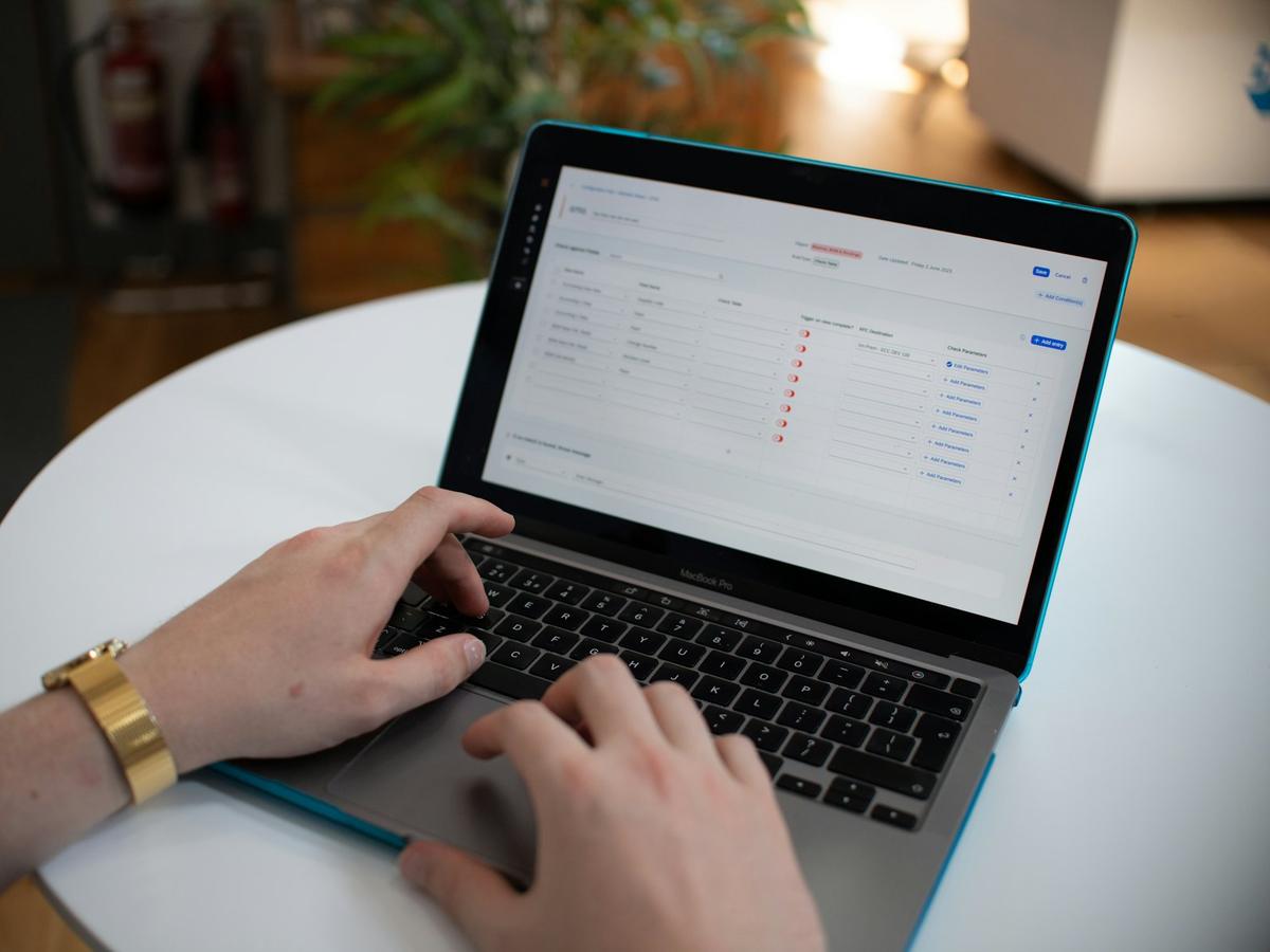 Hands typing on a laptop showing a configuration table of workflow rules