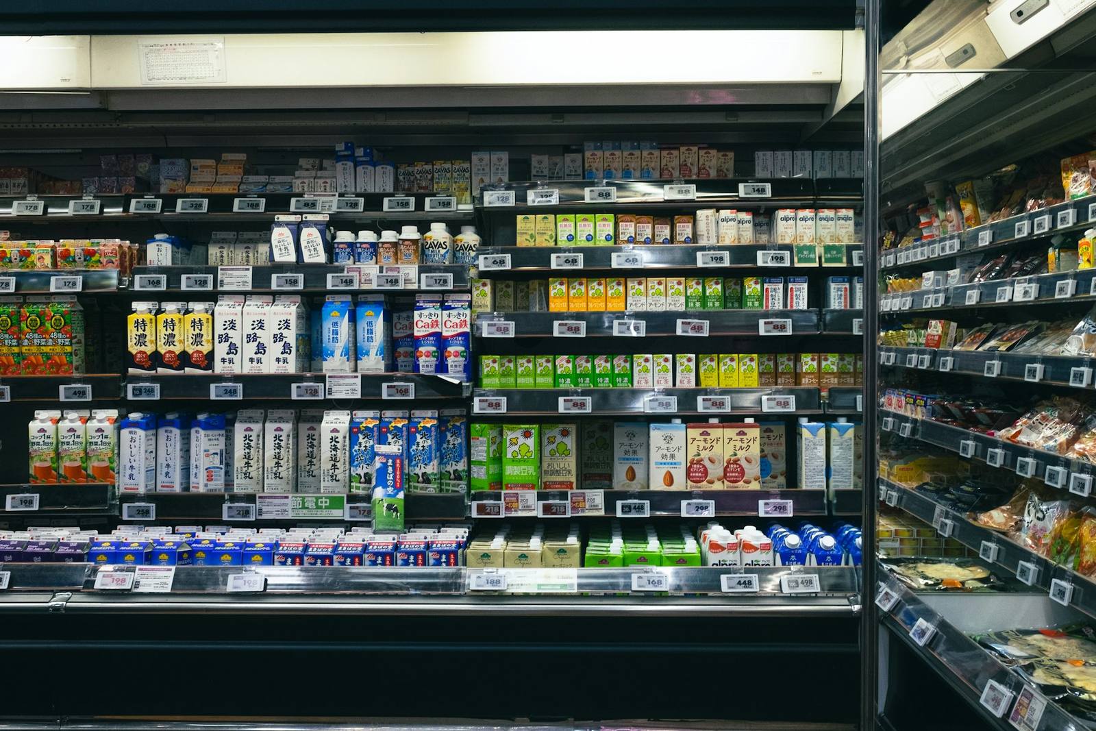 A chilled supermarket shelf stocked with rows of cartons, bottles and packs above electronic price labels