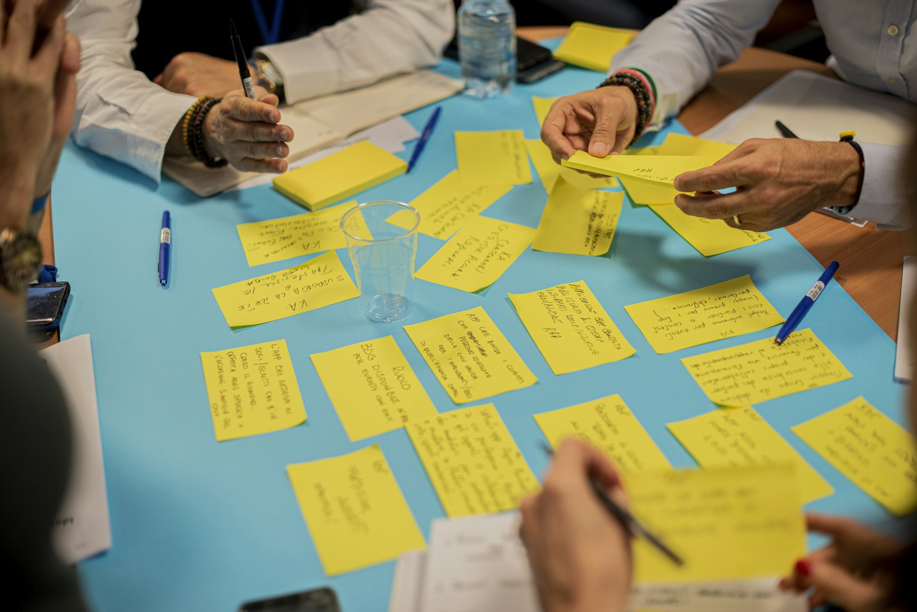 Hands sort handwritten yellow notes across a blue table
