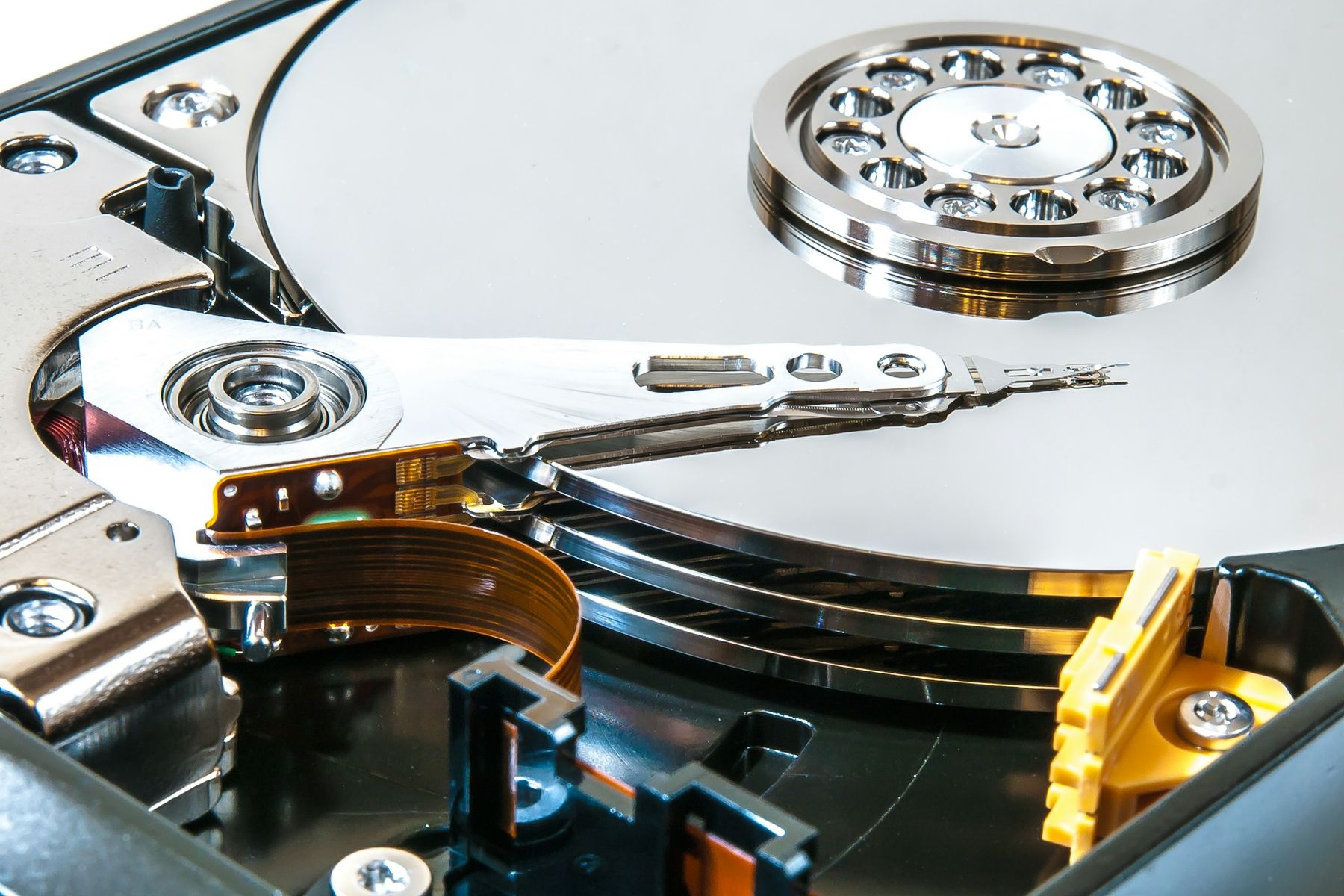The inside of an opened hard drive: a mirrored platter, the read arm and its spindle