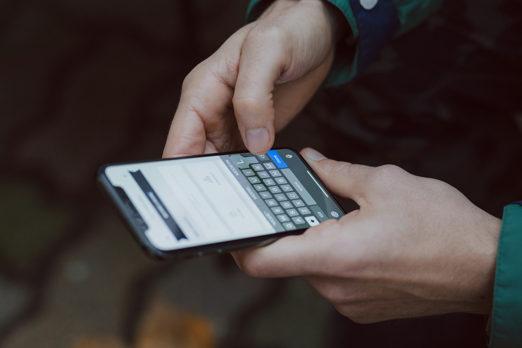 A person holding a phone in both hands, entering details into an on-screen form