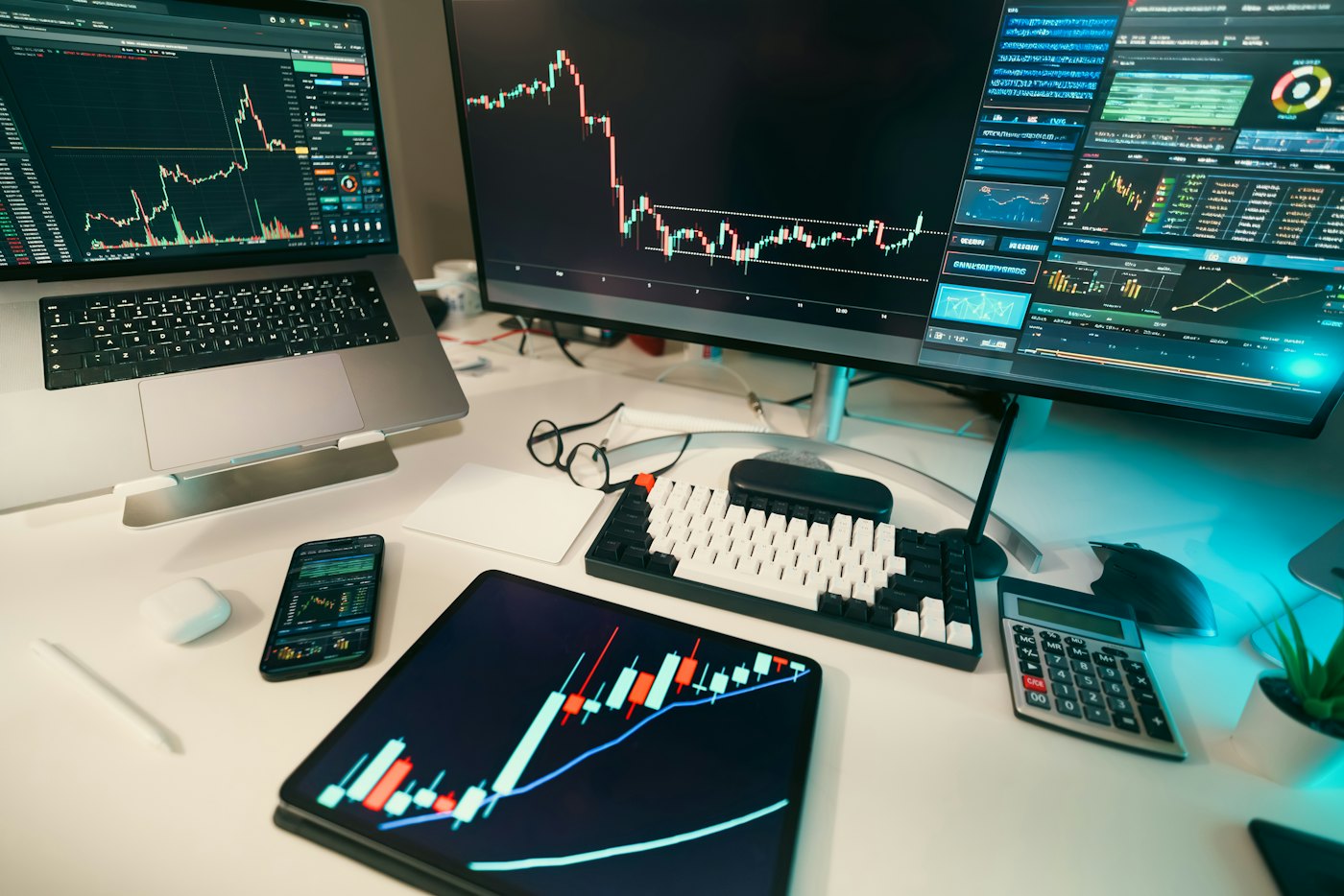 Trading screens and a tablet showing market charts on a desk
