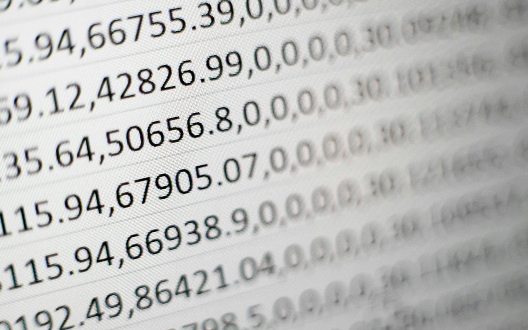 Close-up of a screen full of comma-separated figures, the nearest rows sharp and the rest falling out of focus