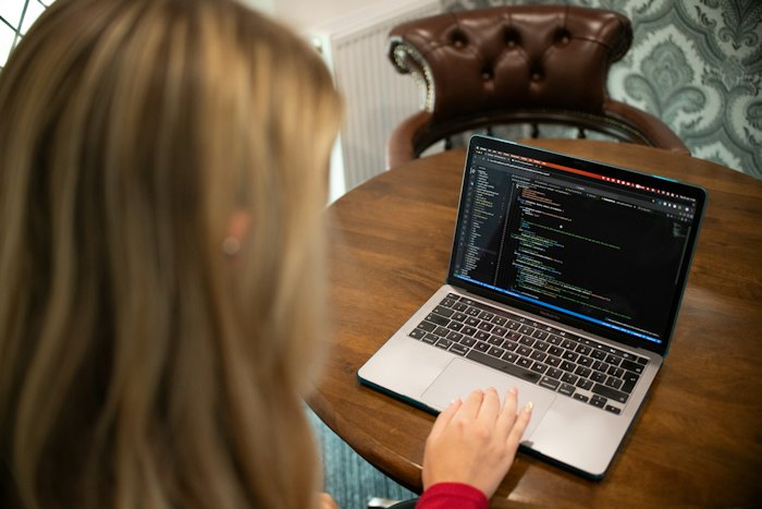 An engineer working through an editor full of code at a table at home