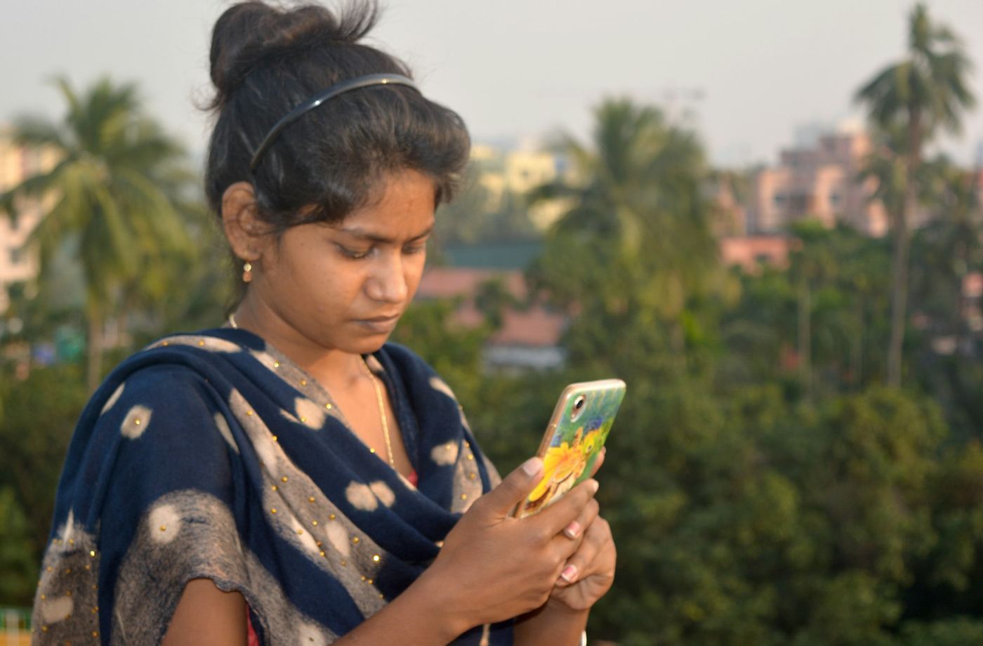 A woman outdoors among trees, reading something on her phone