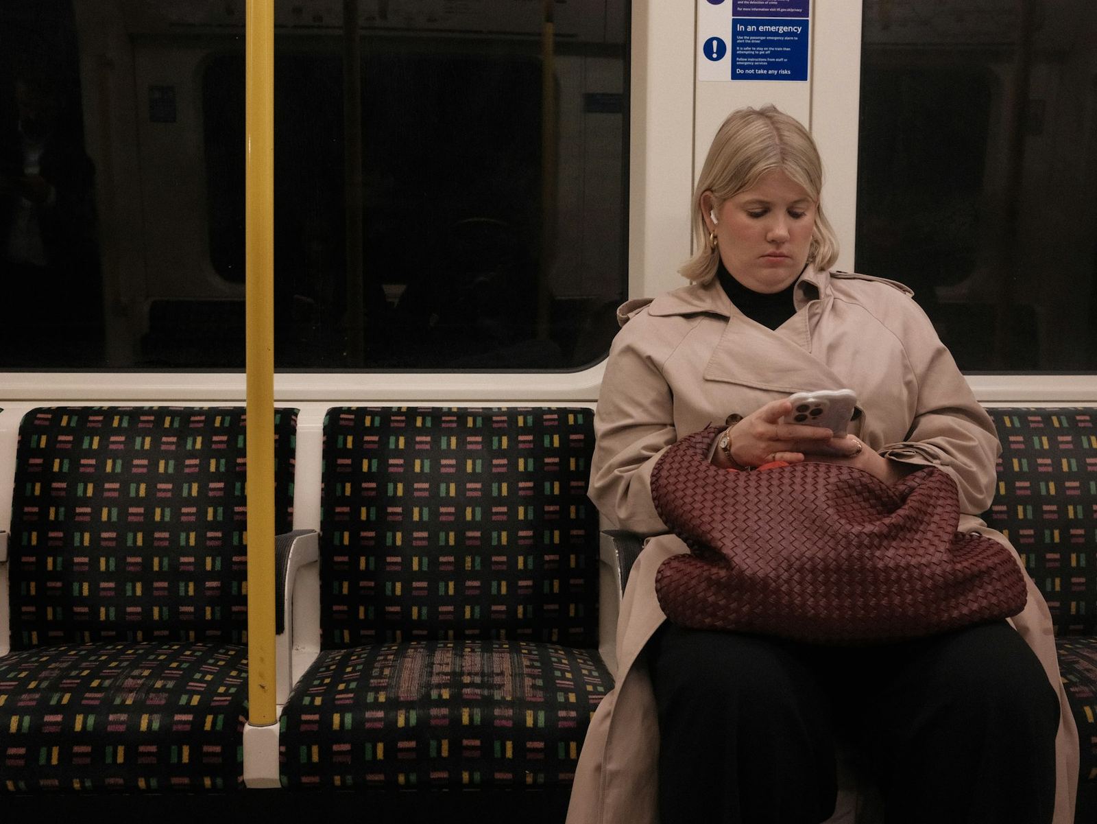 A commuter reading her phone on an underground train