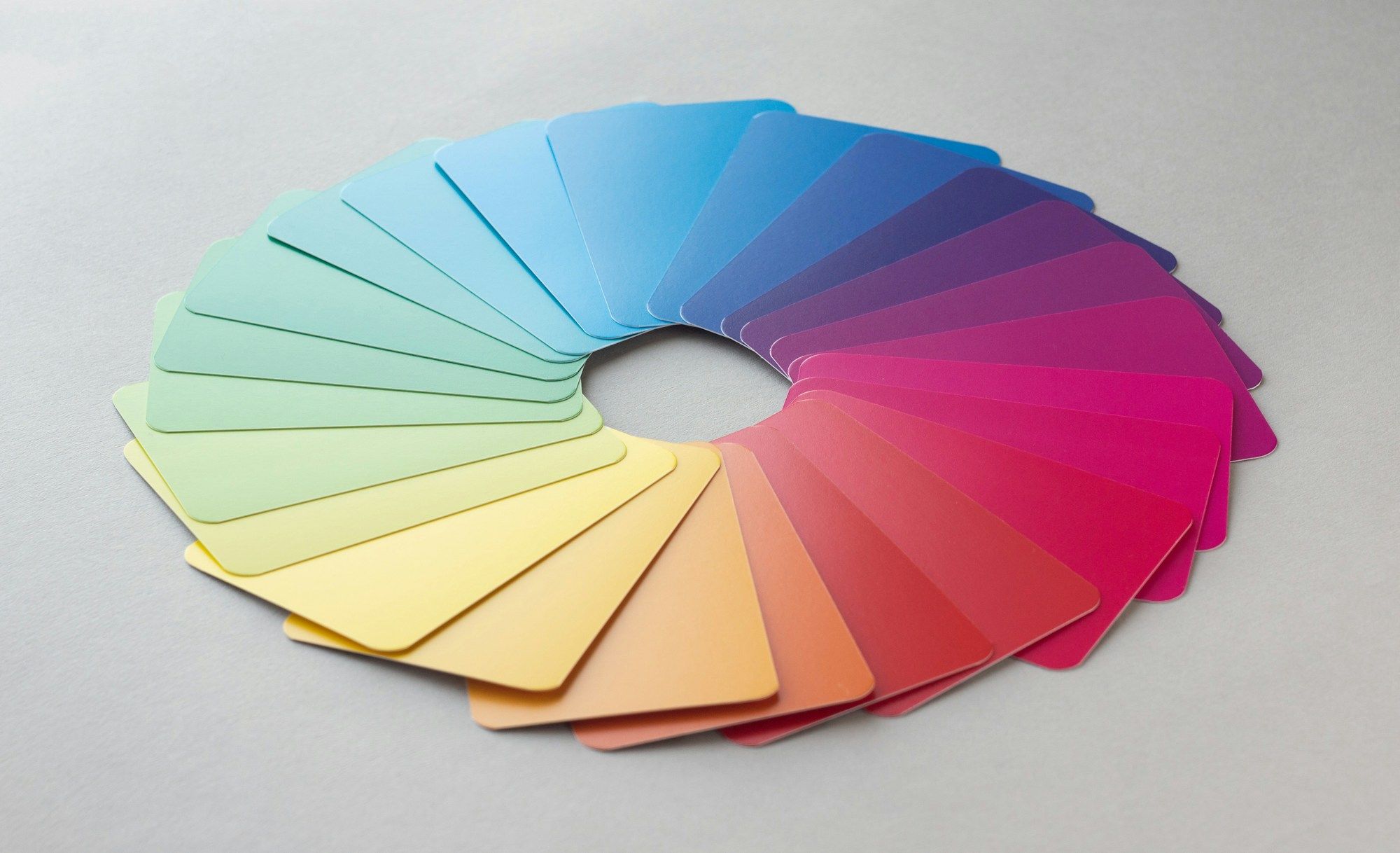 Colour swatch cards fanned into a full circle on a grey surface.