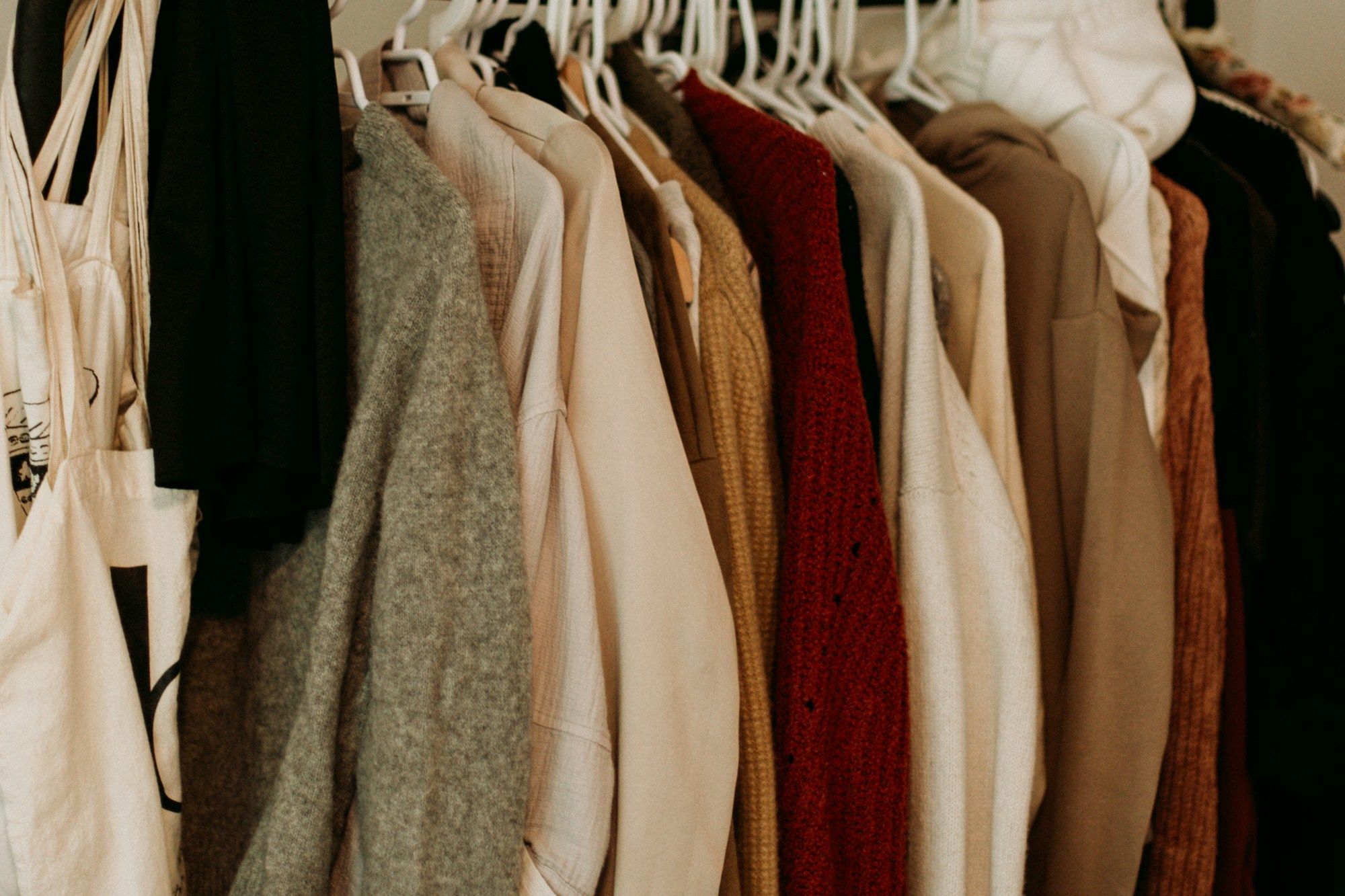 A rail of knitwear and coats in cream, rust, camel and grey.